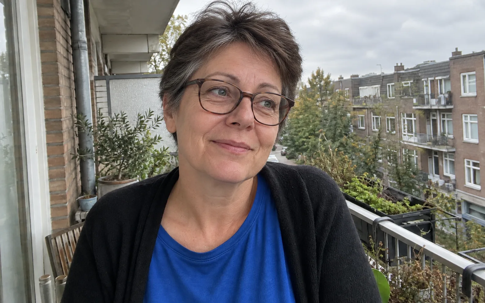 A woman wearing glasses on an apartment balcony