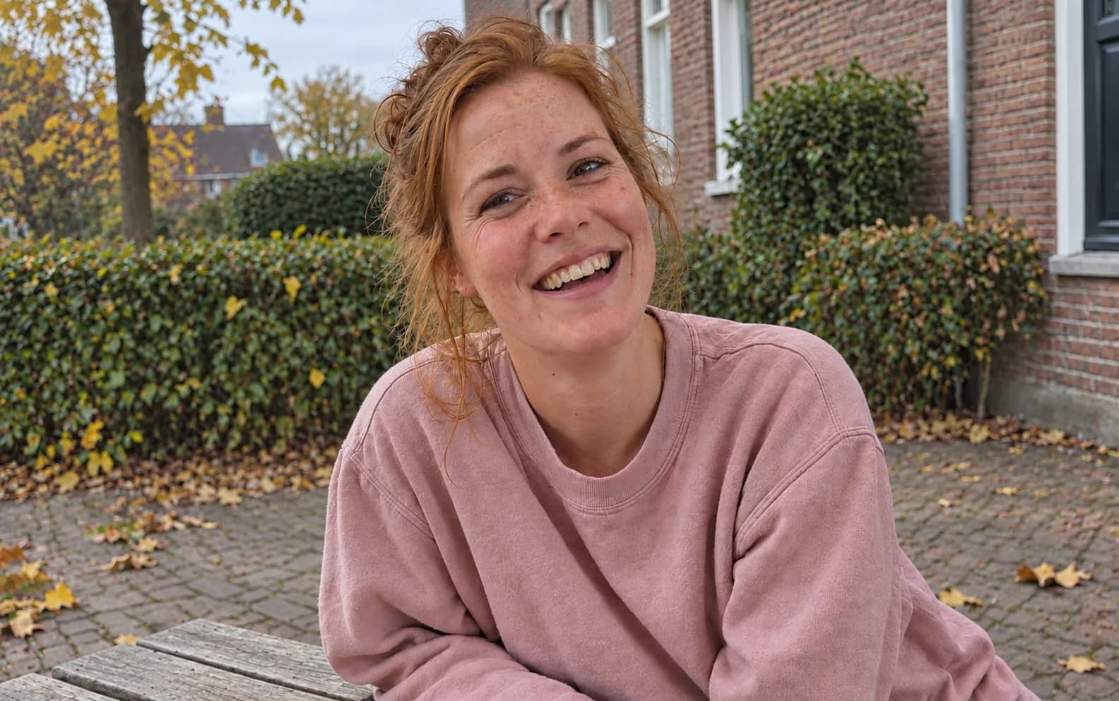 A red-haired woman smiling in a courtyard